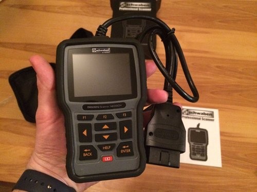 Holding the Schwaben OBD2 scan tool, demonstrating its solid build and ergonomic design for automotive diagnostics.