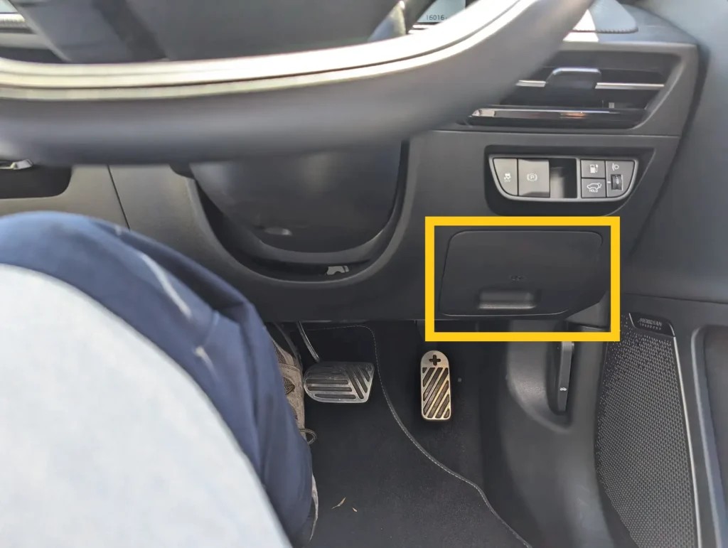 Kia EV6 OBD2 port location under the dashboard on the right side, near the hood release latch in a right-hand drive vehicle.